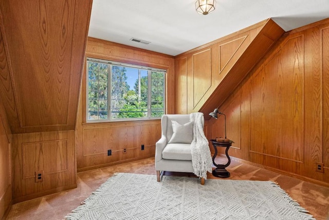 living area with wooden walls and light colored carpet