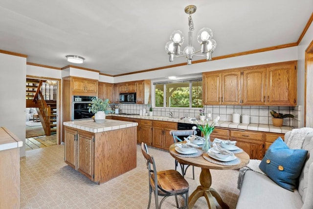 kitchen featuring tasteful backsplash, black appliances, a kitchen island, decorative light fixtures, and tile countertops