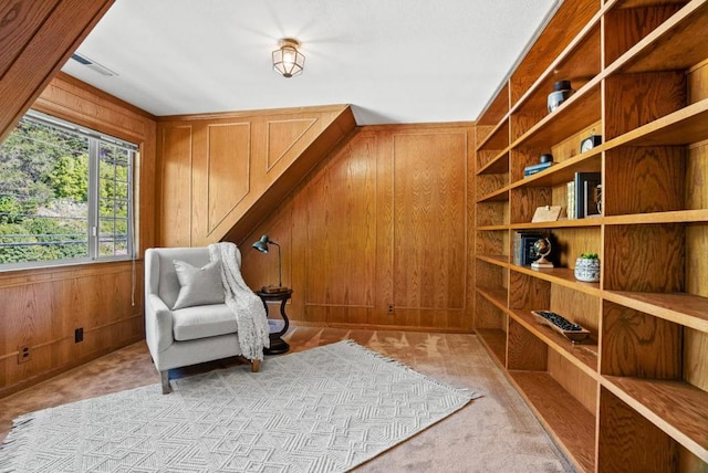 living area featuring light colored carpet and wood walls