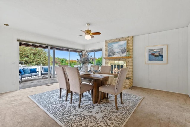 carpeted dining space with a fireplace and ceiling fan