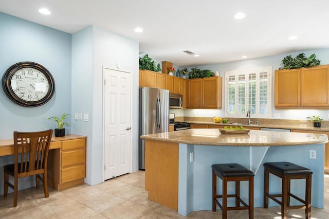 kitchen with a kitchen island, a kitchen bar, sink, and appliances with stainless steel finishes