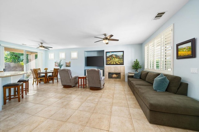 living room with a tile fireplace, ceiling fan, plenty of natural light, and light tile patterned floors