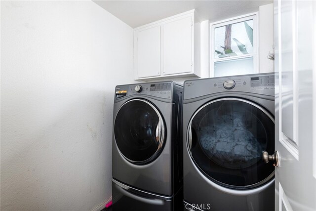 clothes washing area featuring cabinets and washer and dryer