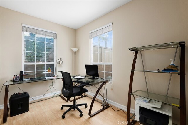 office with light hardwood / wood-style floors and a healthy amount of sunlight