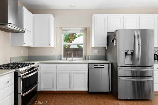 kitchen with white cabinets, sink, wall chimney range hood, and stainless steel appliances