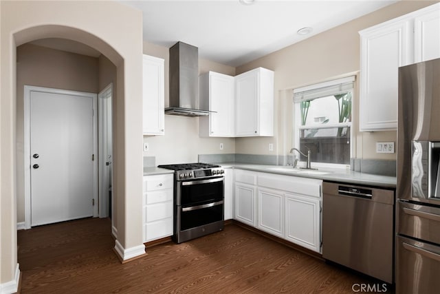 kitchen featuring white cabinets, appliances with stainless steel finishes, wall chimney exhaust hood, and sink