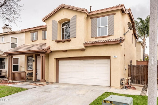 mediterranean / spanish house featuring fence, an attached garage, and stucco siding