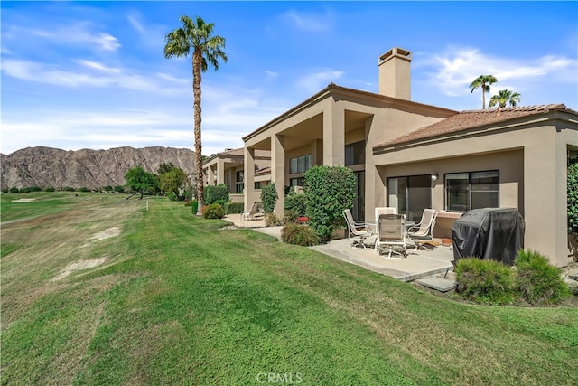 rear view of house featuring a patio, a balcony, a lawn, and a mountain view