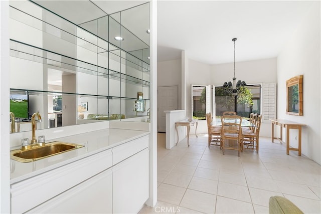 bar featuring light tile patterned flooring, hanging light fixtures, sink, white cabinetry, and an inviting chandelier