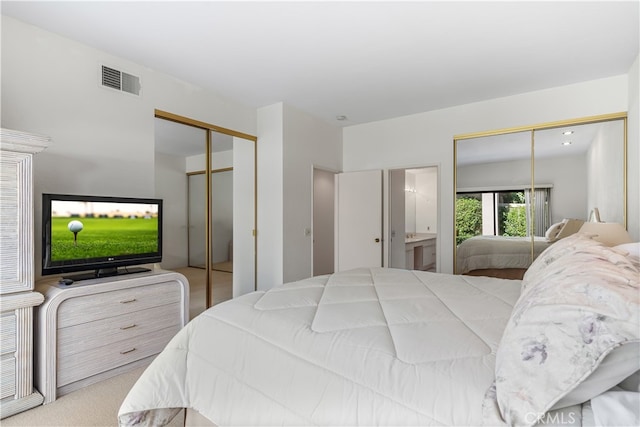 bedroom with light carpet, ensuite bath, and two closets