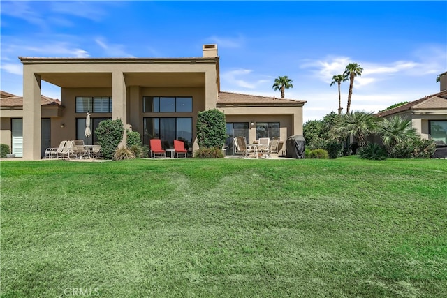 back of property with a lawn and a patio area