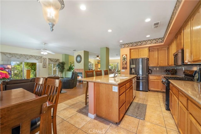 kitchen with stainless steel appliances, ceiling fan, a kitchen island with sink, sink, and light tile patterned flooring