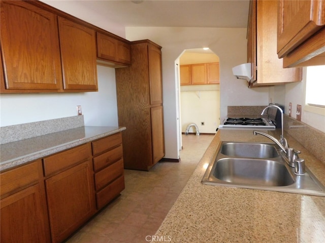 kitchen featuring stainless steel stove, sink, and ventilation hood