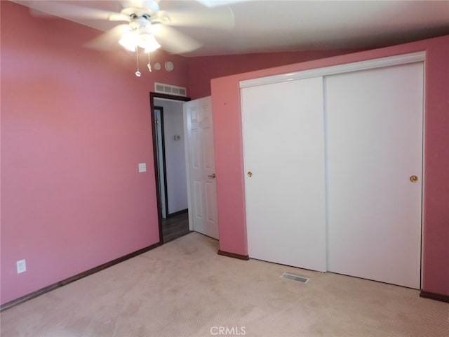 unfurnished bedroom featuring vaulted ceiling, light carpet, ceiling fan, and a closet