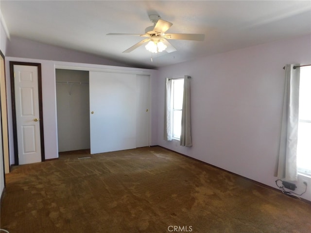 unfurnished bedroom featuring lofted ceiling, dark carpet, and ceiling fan