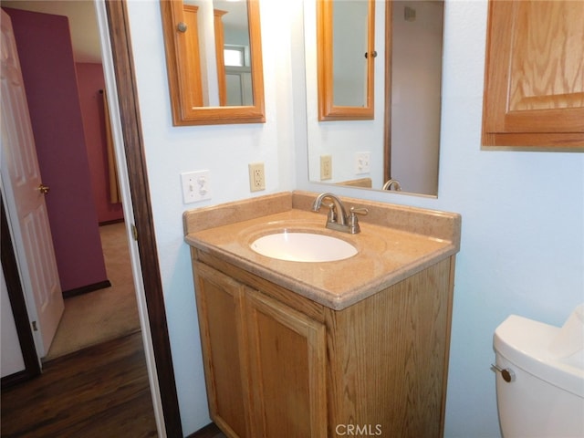 bathroom with wood-type flooring, vanity, and toilet