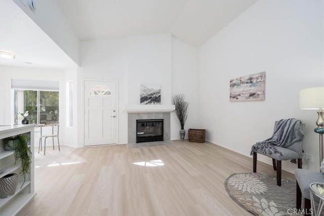 living area featuring a fireplace, light hardwood / wood-style flooring, and lofted ceiling