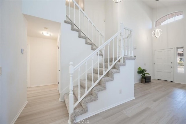 foyer entrance featuring a towering ceiling and light wood-type flooring