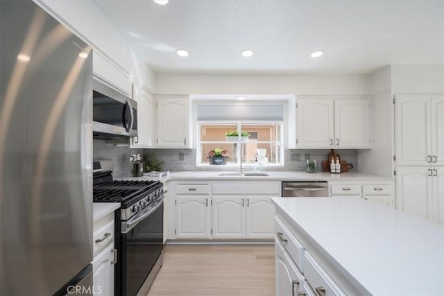 kitchen with tasteful backsplash, stainless steel appliances, sink, light hardwood / wood-style flooring, and white cabinets