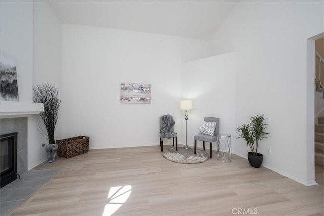 sitting room featuring a tile fireplace, vaulted ceiling, and light wood-type flooring