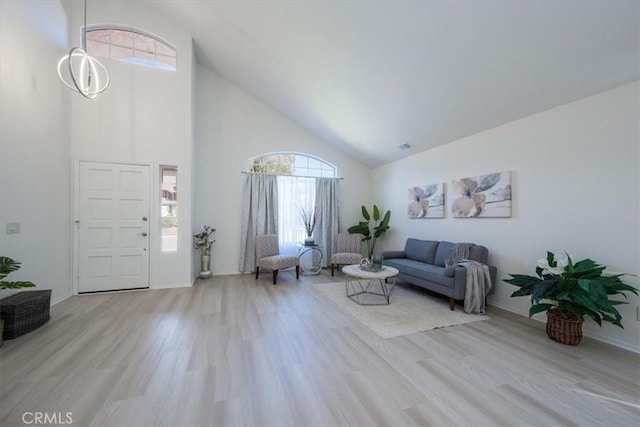 living room with high vaulted ceiling, light hardwood / wood-style floors, and a notable chandelier