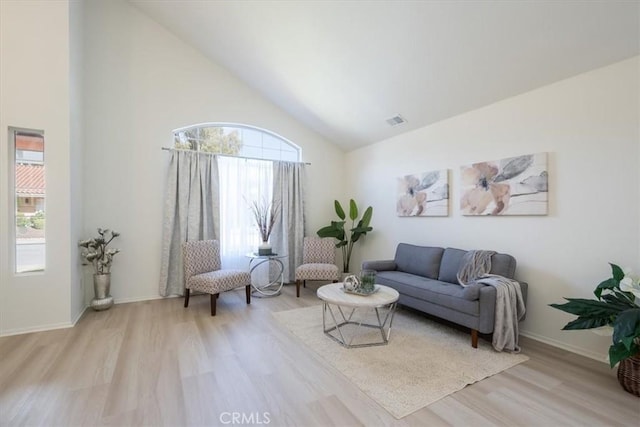 living room featuring high vaulted ceiling and light wood-type flooring