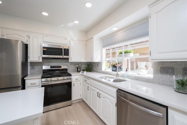 kitchen featuring decorative backsplash, appliances with stainless steel finishes, white cabinetry, and sink