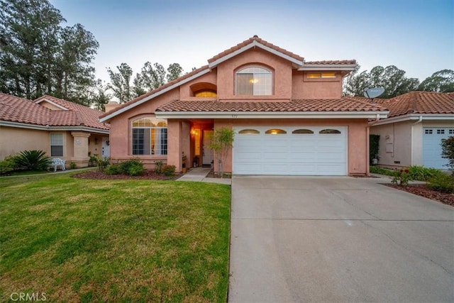 mediterranean / spanish home with a garage and a front lawn