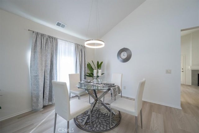 dining area featuring vaulted ceiling and light hardwood / wood-style flooring