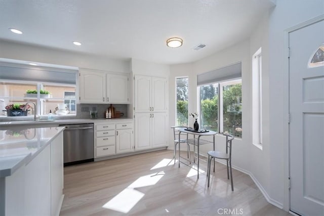 kitchen featuring backsplash, white cabinets, sink, dishwasher, and light hardwood / wood-style floors