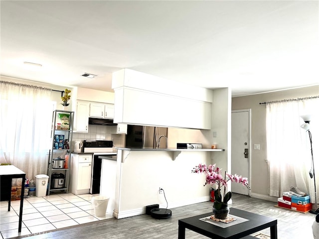 kitchen with light hardwood / wood-style flooring, white cabinets, white range with electric stovetop, and stainless steel fridge