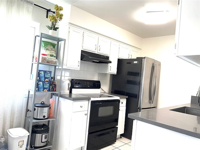 kitchen with black electric range, tasteful backsplash, white cabinets, light tile patterned floors, and stainless steel fridge