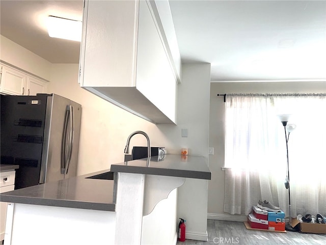 kitchen with light hardwood / wood-style flooring, white cabinets, sink, and stainless steel refrigerator