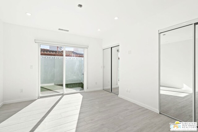 unfurnished bedroom with access to outside and light hardwood / wood-style flooring