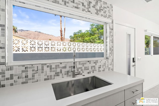 kitchen featuring a mountain view, decorative backsplash, and sink