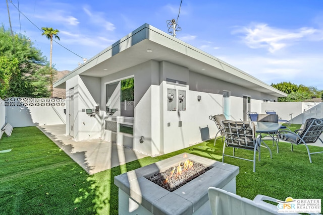 back of house with a fire pit, a patio area, and a yard