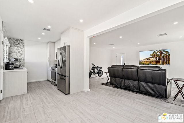 kitchen featuring appliances with stainless steel finishes, light wood-type flooring, white cabinetry, and sink