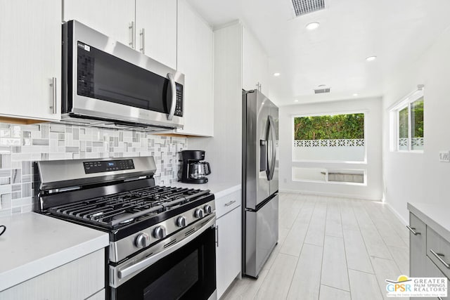 kitchen featuring decorative backsplash, white cabinets, and stainless steel appliances