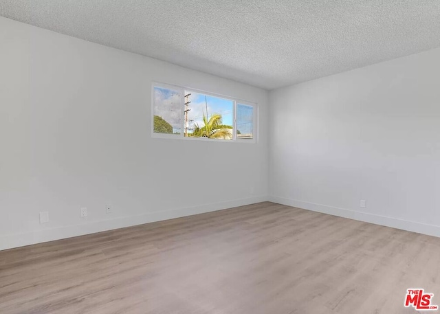 unfurnished room with a textured ceiling and light wood-type flooring