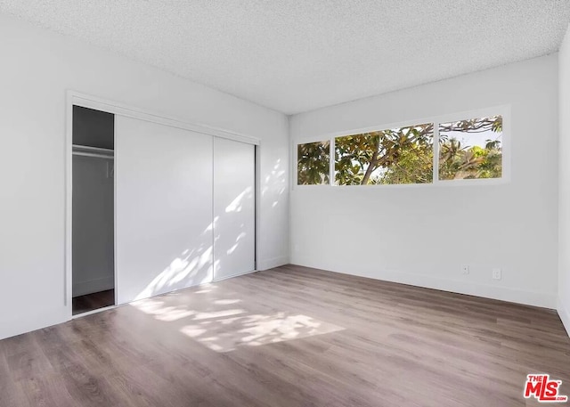 unfurnished bedroom featuring a textured ceiling, hardwood / wood-style flooring, and a closet