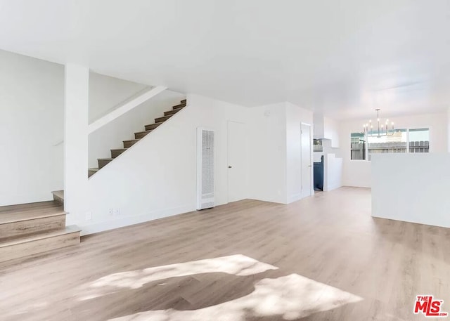 unfurnished living room with a notable chandelier and light hardwood / wood-style floors