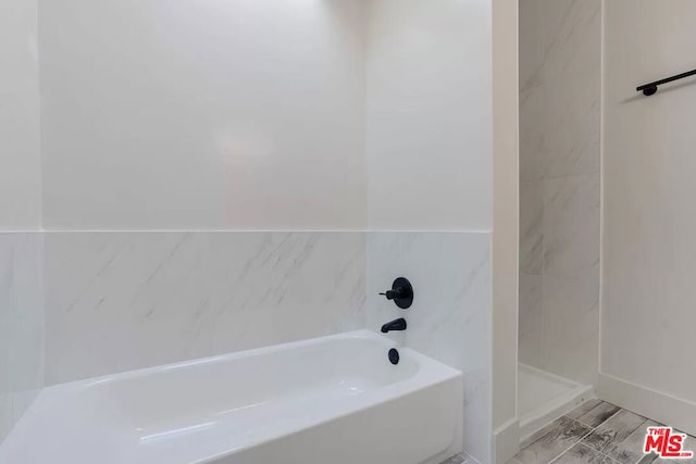 bathroom featuring hardwood / wood-style flooring, a bath, and tile walls