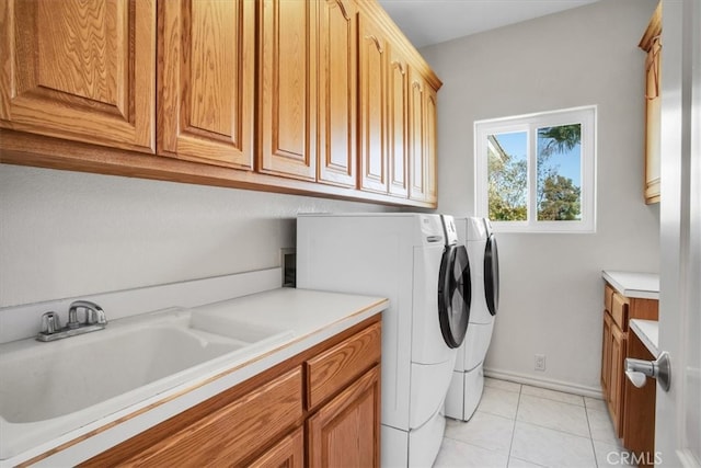 laundry room with washer and clothes dryer, light tile patterned floors, cabinets, and sink