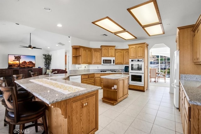 kitchen with white appliances, kitchen peninsula, a breakfast bar area, lofted ceiling, and a center island