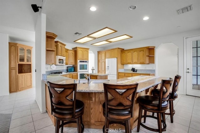 kitchen featuring a breakfast bar, white appliances, light tile patterned flooring, and sink