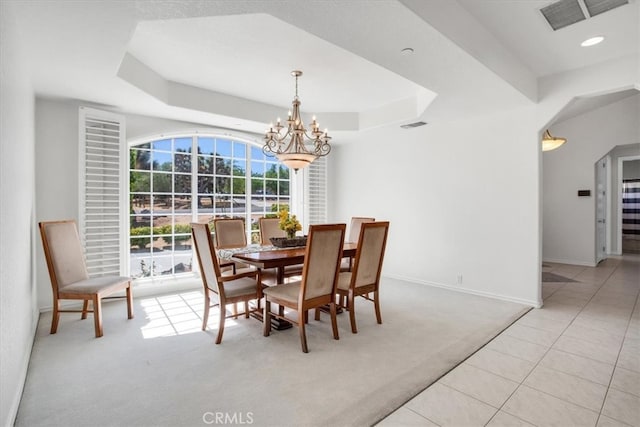 carpeted dining room with a notable chandelier and a raised ceiling