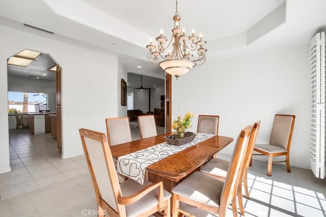 dining area featuring an inviting chandelier, a raised ceiling, and light tile patterned floors