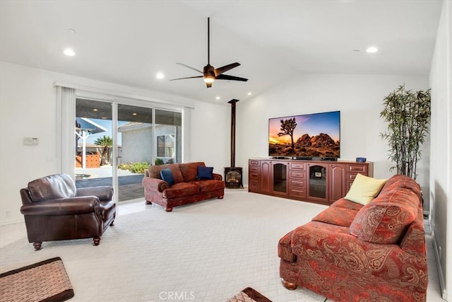 living room featuring a wood stove, lofted ceiling, ceiling fan, and light colored carpet