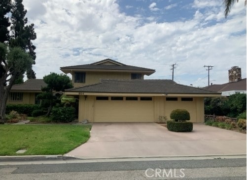 view of front of property featuring driveway, a garage, and a front yard