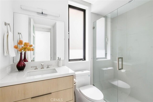 bathroom with a shower with door, vanity, and toilet